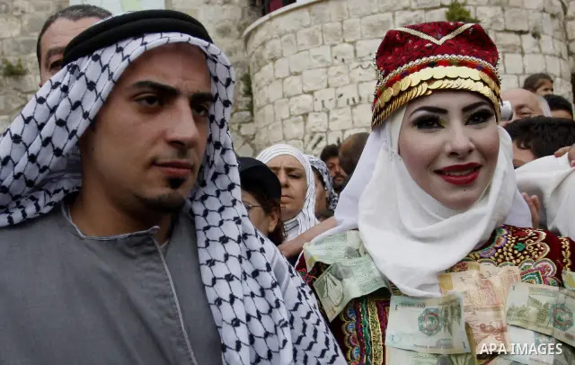 The Palestinian bride and groom Mhaha Salam (R) and Thayer Qasem (L), walk down the street on their wedding day on April 12, 2012 after they traveled from the refugee camp of al-Yarmuk in Syria, to get married in the Wes...