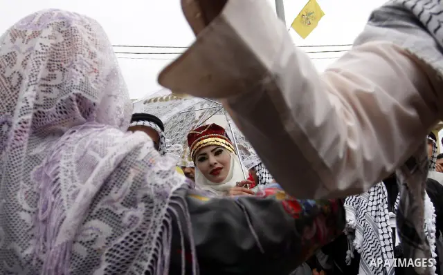 The Palestinian bride and groom Mhaha Salam (R) and Thayer Qasem (L), walk down the street on their wedding day on April 12, 2012 after they traveled from the refugee camp of al-Yarmuk in Syria, to get married in the Wes...