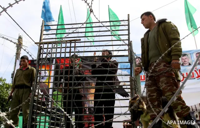 Hamas supporters acting as Palestinian prisoners stand in a mock cage during a rally in Jabalya, in the northern Gaza Strip, April 13, 2012, calling for the release of Palestinian prisoners from Israeli jails. Photo by M...