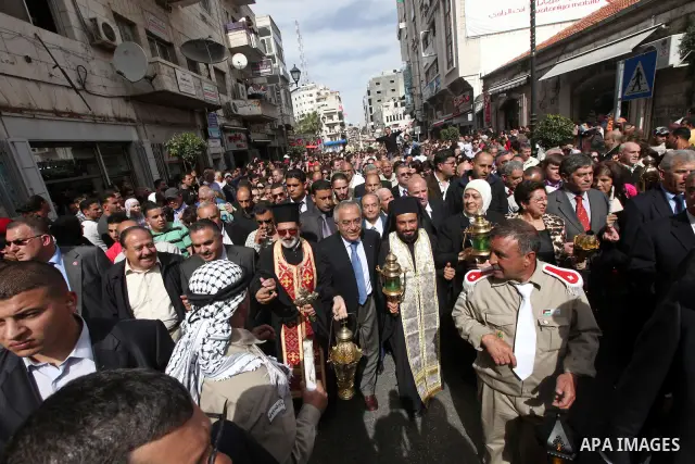 Palestinian Prime Minister Salam Fayyad takes part in the "Holy Fire" procession on the eve of Orthodox Easter in the West Bank city of Ramallah on April 14, 2012. The date of Orthodox Easter is calculated differently th...