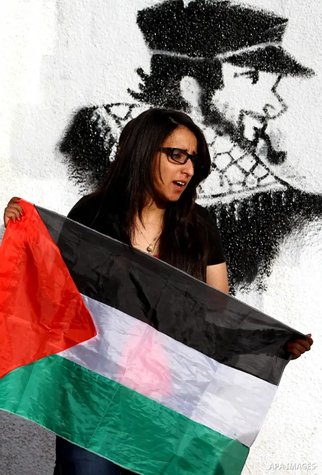 A Palestinian artist puts the final touches on a black and white mural painting dedicated to late Italian activist Vittorio Arrigoni in Gaza City on April 14, 2012, as Gazans marked the first anniversary of his murder in...