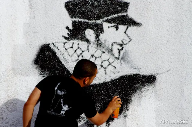 A Palestinian artist puts the final touches on a black and white mural painting dedicated to late Italian activist Vittorio Arrigoni in Gaza City on April 14, 2012, as Gazans marked the first anniversary of his murder in...