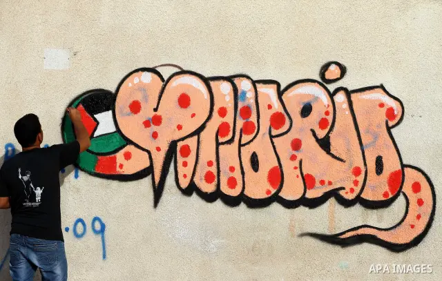 A Palestinian artist puts the final touches on a black and white mural painting dedicated to late Italian activist Vittorio Arrigoni in Gaza City on April 14, 2012, as Gazans marked the first anniversary of his murder in...
