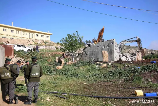Israeli border police officers stand guard as demolition vehicles destroy a man-made reservoir on a Palestinian farm near the West Bank city of Hebron, on Apr. 16, 2012. Reports state that tensions rose as Palestinian ho...