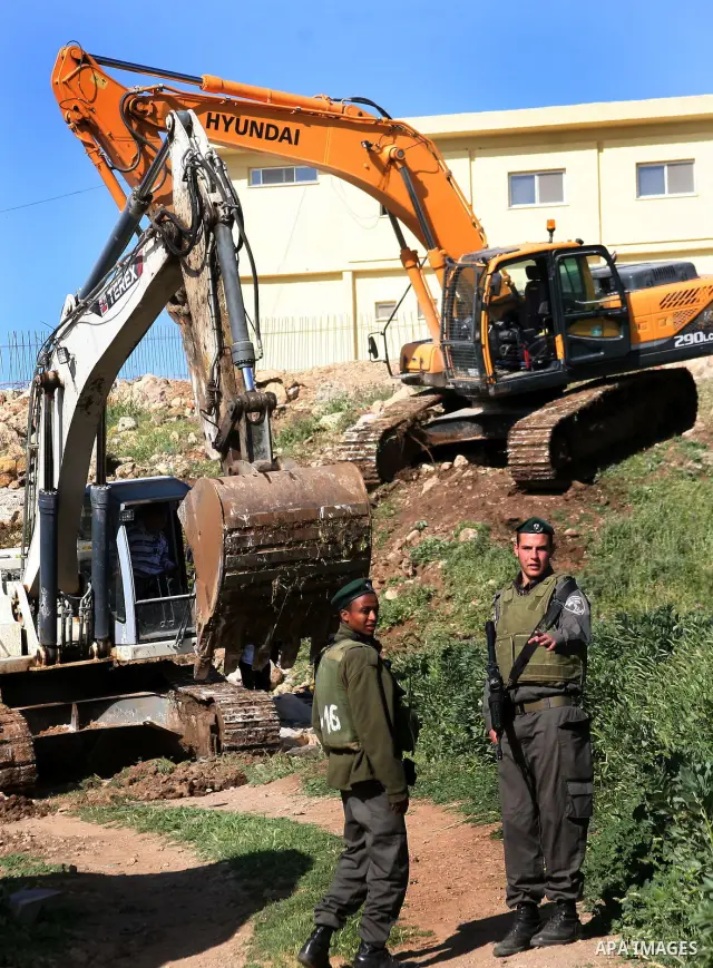 Israeli border police officers stand guard as demolition vehicles destroy a man-made reservoir on a Palestinian farm near the West Bank city of Hebron, on Apr. 16, 2012. Reports state that tensions rose as Palestinian ho...