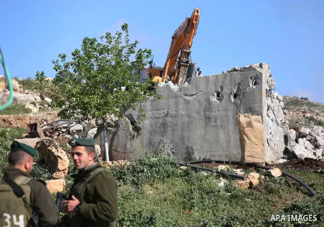 Israeli border police officers stand guard as demolition vehicles destroy a man-made reservoir on a Palestinian farm near the West Bank city of Hebron, on Apr. 16, 2012. Reports state that tensions rose as Palestinian ho...