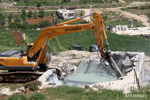 Israeli Border Police stand by as a security bulldozer demolishes a water storage tank owned by the Palestinians in the village of Dura, outside the West Bank city of Hebron, 16 April 2012. The reservoir building was dem...