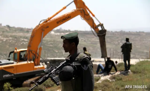 Israeli Border Police stand by as a security bulldozer demolishes a water storage tank owned by the Palestinians in the village of Dura, outside the West Bank city of Hebron, 16 April 2012. The reservoir building was dem...