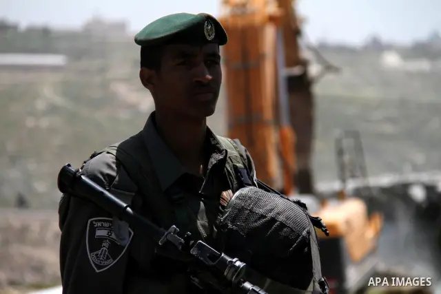 Israeli Border Police stand by as a security bulldozer demolishes a water storage tank owned by the Palestinians in the village of Dura, outside the West Bank city of Hebron, 16 April 2012. The reservoir building was dem...