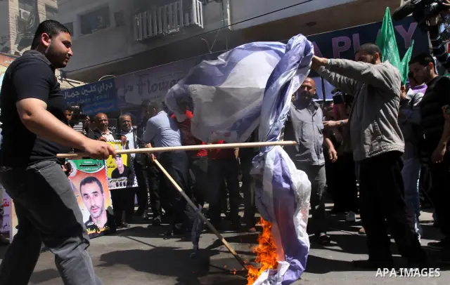 Palestinians burn Israel's national flag during a rally in front of the Red Cross headquarters in Gaza City marking Palestinian Prisoners Day April 17, 2012. The Israeli Prisons Authority said on Tuesday in a written sta...