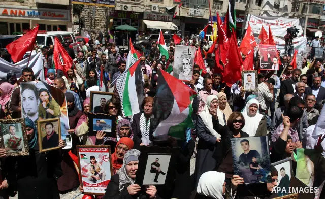 Palestinians hold a photograph of a prisoner jailed in Israel, during a rally marking the annual prisoners' day in the West Bank city of Ramallah, Tuesday, April 17, 2012. Hundreds of Palestinian prisoners held by Israel...
