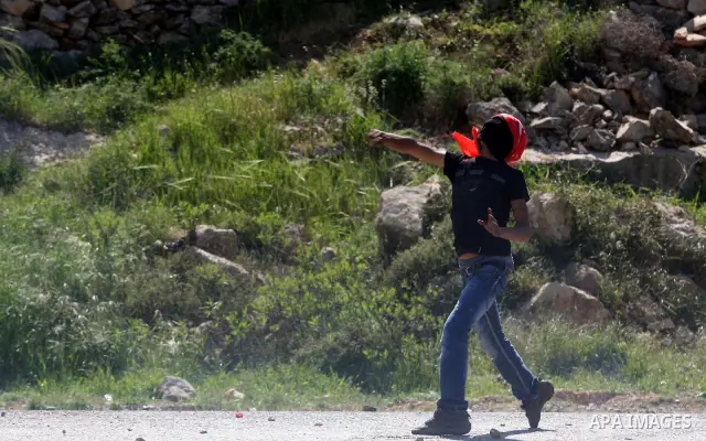 A Palestinian protester throws a stone towards the Israeli soldiers during clashes following a demonstration to mark the Prisoners' Day near Israels Ofr prison, between Jerusalem and Ramallah on April 17, 2012. At least...