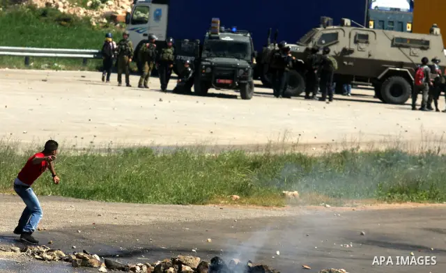 A Palestinian protester throws a stone towards the Israeli soldiers during clashes following a demonstration to mark the Prisoners' Day near Israels Ofr prison, between Jerusalem and Ramallah on April 17, 2012. At least...
