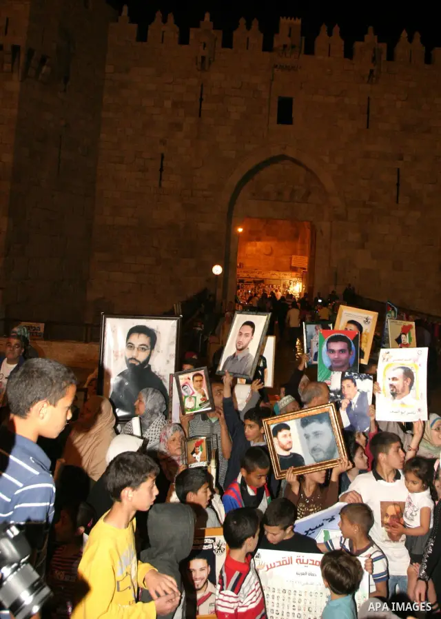 Palestinians hold portraits of relatives jailed in Israeli prisons as they protest to demand for their release during a demonstration to mark Prisoners' Day outside the Damascus gate, in the old city of Jerusalem on Apri...