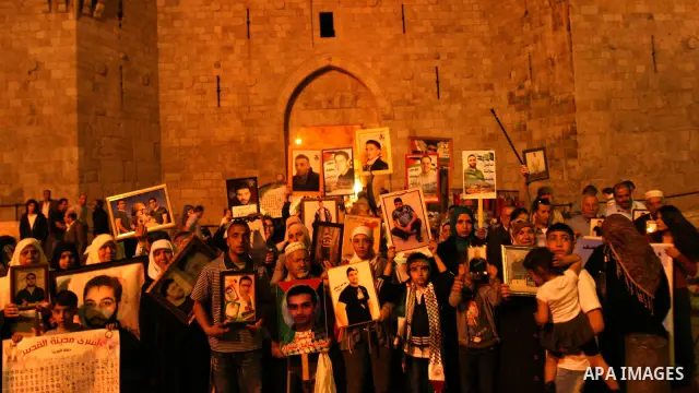 Palestinians hold portraits of relatives jailed in Israeli prisons as they protest to demand for their release during a demonstration to mark Prisoners' Day outside the Damascus gate, in the old city of Jerusalem on Apri...