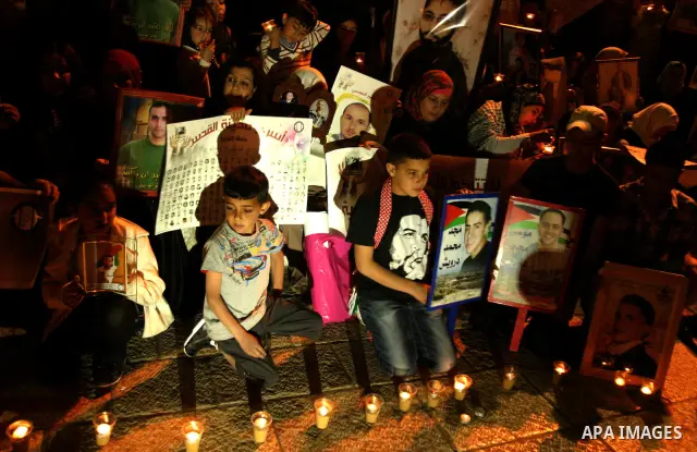 Palestinians hold portraits of relatives jailed in Israeli prisons as they protest to demand for their release during a demonstration to mark Prisoners' Day outside the Damascus gate, in the old city of Jerusalem on Apri...