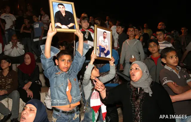 Palestinians hold portraits of relatives jailed in Israeli prisons as they protest to demand for their release during a demonstration to mark Prisoners' Day outside the Damascus gate, in the old city of Jerusalem on Apri...