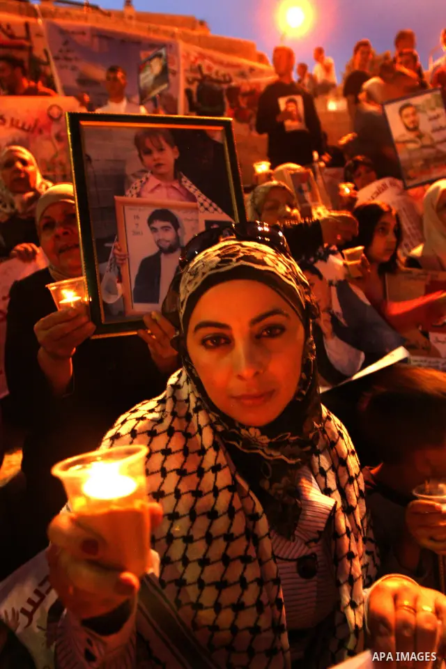 Palestinians hold portraits of relatives jailed in Israeli prisons as they protest to demand for their release during a demonstration to mark Prisoners' Day outside the Damascus gate, in the old city of Jerusalem on Apri...