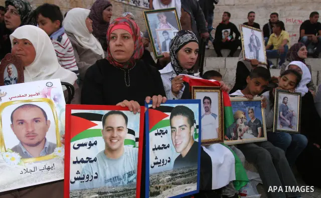 Palestinians hold portraits of relatives jailed in Israeli prisons as they protest to demand for their release during a demonstration to mark Prisoners' Day outside the Damascus gate, in the old city of Jerusalem on Apri...