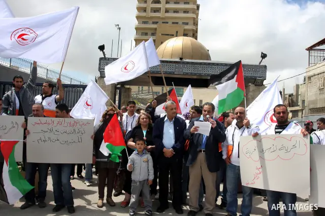 Staff of the Palestinian Red Crescent Society, wave flags and banners during a rally in solidarity with prisoners in Israeli jails, in the West Bank city of Ramallah, April 19, 2012. Photo by Issam Rimawi