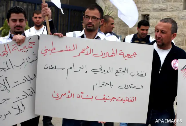 Staff of the Palestinian Red Crescent Society, wave flags and banners during a rally in solidarity with prisoners in Israeli jails, in the West Bank city of Ramallah, April 19, 2012. Photo by Issam Rimawi
