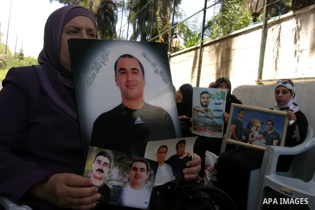 Palestinians hold pictures of a relatives currently being held in an Israeli jail, during a rally outside of the International Red Cross building in east Jerusalem, on April 20, 2012. Photo by Mahfouz Abu Turk
