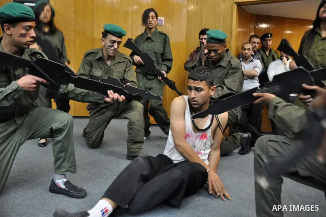 Palestinian actors from Al-Najah university, perform a play, appear Israeli soldiers arrest a Palestinian youth and investigate him in the West Bank city of Nablus, on April,22 2012. Photo by Nedal Eshtaya