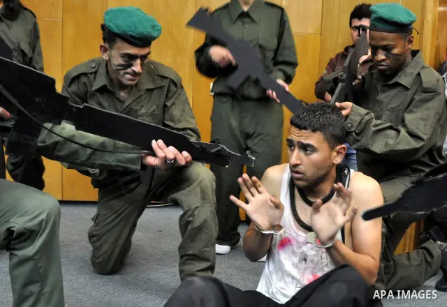 Palestinian actors from Al-Najah university, perform a play, appear Israeli soldiers arrest a Palestinian youth and investigate him in the West Bank city of Nablus, on April,22 2012. Photo by Nedal Eshtaya