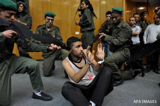 Palestinian actors from Al-Najah university, perform a play, appear Israeli soldiers arrest a Palestinian youth and investigate him in the West Bank city of Nablus, on April,22 2012. Photo by Nedal Eshtaya