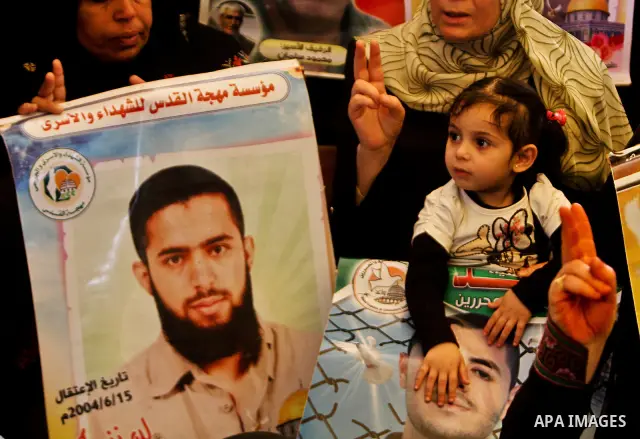 A Palestinian woman holding up a portrait of a jailed loved one takes part in a protest outside the Red Cross offices in Gaza City on April 23, 2012. Photo by Ali Jadallah