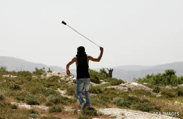 A Palestinian throws a rock toward a Jewish settler during clashes near their school at Oref Village near the West Bank City of Nablus on 23 April 2012 .Israeli settlers from Jewish settlement of Yetshar attacked the sch...
