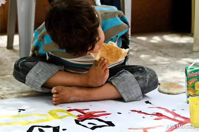 A Palestinian disabled child uses his feet to eat bread at a charity association during a celebration in Gaza city on April 23,2012. Photo by Ali Jadallah