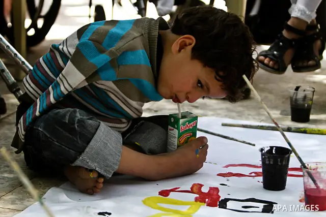 A Palestinian disabled child uses his feet to drink juice at a charity association during a celebration in Gaza city on April 23,2012. Photo by Ali Jadallah