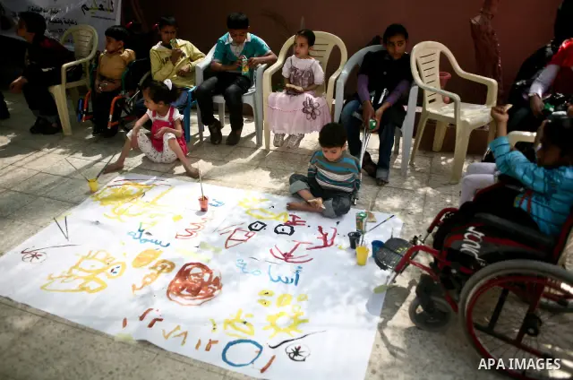Palestinian disabled children use their feet to draw and paint pictures at a charity association during a celebration in Gaza city on April 23,2012. Photo by Ali Jadallah