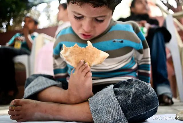 A Palestinian disabled child uses his feet to eat bread at a charity association during a celebration in Gaza city on April 23,2012. Photo by Ali Jadallah