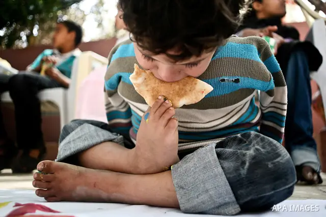 A Palestinian disabled child uses his feet to eat bread at a charity association during a celebration in Gaza city on April 23,2012. Photo by Ali Jadallah