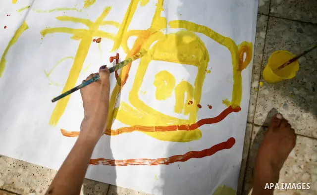 A Palestinian disabled child uses his feet to draw and paint pictures at a charity association during a celebration in Gaza city on April 23,2012. Photo by Ali Jadallah