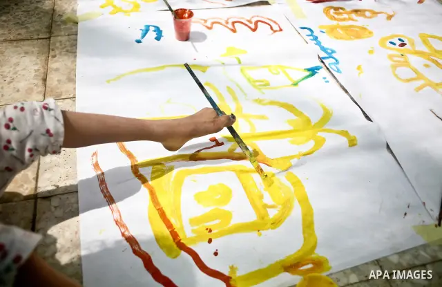 A Palestinian disabled child uses his feet to draw and paint pictures at a charity association during a celebration in Gaza city on April 23,2012. Photo by Ali Jadallah