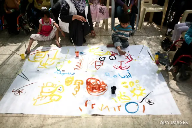Palestinian disabled children use their feet to draw and paint pictures at a charity association during a celebration in Gaza city on April 23,2012. Photo by Ali Jadallah