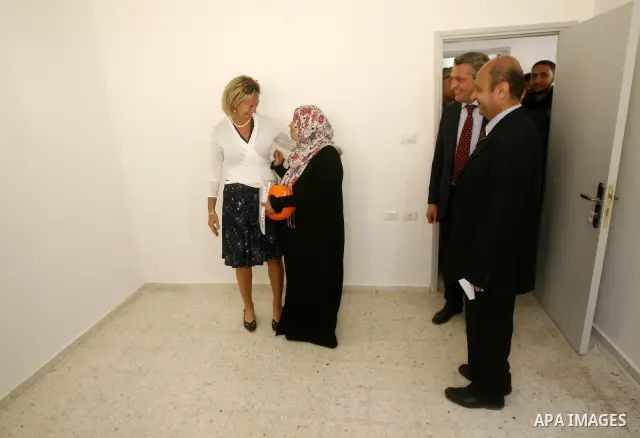 Birgitta Tazelaar head of the Netherlands Representation to the Palestinian Authority, watches alongside UNRWA's Filippo Grandi as a Palestinian woman prepares to enter her new home, after receving a donation from the Du...
