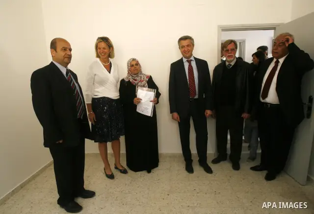 Birgitta Tazelaar head of the Netherlands Representation to the Palestinian Authority, watches alongside UNRWA's Filippo Grandi as a Palestinian woman prepares to enter her new home, after receving a donation from the Du...