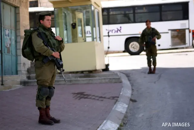 Israeli soldier stands during pray in front of a Jewish cemetery near the settlement of Tel Rumeida, in the West Bank City of Hebron, on April 25, 2012. Photo by Mamoun Wazwaz