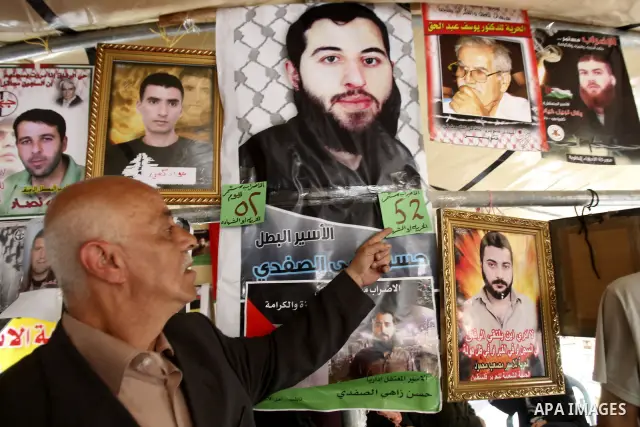 Palestinian man stands near portraits for prisoners jailed in Israel during a demonstration calling for their release, in the West Bank city of Nablus on April 25, 2012. Photo by Wagdi Eshtayah