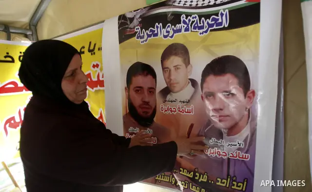 Palestinian woman stands near portraits for prisoners jailed in Israel during a demonstration calling for their release, in the West Bank city of Nablus on April 25, 2012. Photo by Wagdi Eshtayah