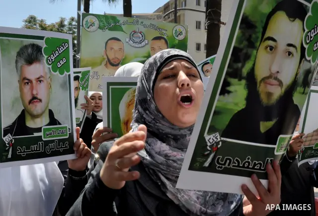 Palestinian woman stands near portraits for prisoners jailed in Israel during a demonstration calling for their release, in the West Bank city of Nablus on April 25, 2012. Photo by Nedal Eshtayah