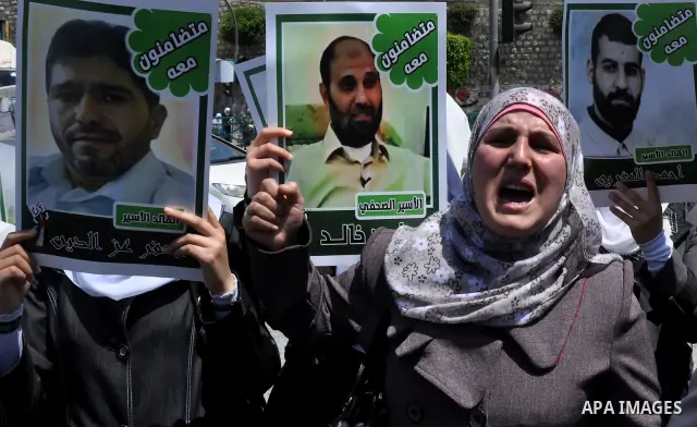 Palestinian woman stands near portraits for prisoners jailed in Israel during a demonstration calling for their release, in the West Bank city of Nablus on April 25, 2012. Photo by Nedal Eshtayah