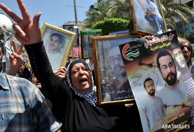 Palestinian woman stands near portraits for prisoners jailed in Israel during a demonstration calling for their release, in the West Bank city of Nablus on April 25, 2012. Photo by Nedal Eshtayah