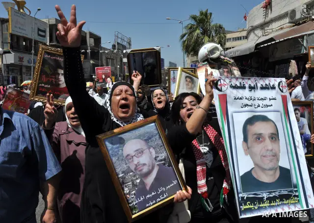 Palestinian woman stands near portraits for prisoners jailed in Israel during a demonstration calling for their release, in the West Bank city of Nablus on April 25, 2012. Photo by Nedal Eshtayah