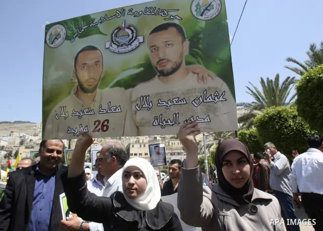 Palestinian woman stands near portraits for prisoners jailed in Israel during a demonstration calling for their release, in the West Bank city of Nablus on April 25, 2012. Photo by Wagdi Eshtayah