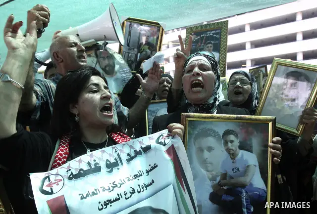 Palestinian woman stands near portraits for prisoners jailed in Israel during a demonstration calling for their release, in the West Bank city of Nablus on April 25, 2012. Photo by Wagdi Eshtayah